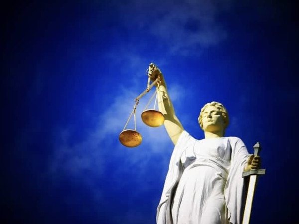 Vrouwe Justitia onder een blauwe lucht met een zwaard en weegschaal in haar hand