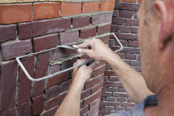 Een metselaar werkt de voegen van een bakstenen muur af.